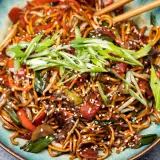 Chao mian Nudeln mit Gemüse, garniert mit Frühlingszwiebeln und Sesam.