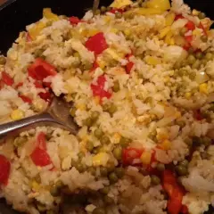 Ein köstlicher kantonesischer Reis mit Erbsen, Paprika und Mais, serviert in einer Pfanne.