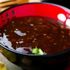 Schwarze Schale mit Teriyaki-Sauce, Ingwer und Honig. Der Geschmack von Teriyaki-Sauce ist süßlich-salzig und würzig.