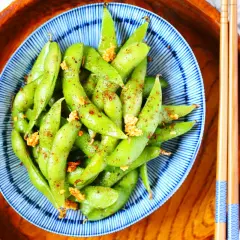 Schüssel mit gewürzten Edamame-Schoten, eine gesunde Quelle für Edamame Proteine, bereit zum Genuss mit Stäbchen.