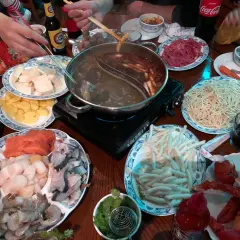 Ein Tisch voller Köstlichkeiten: Was ist Hot Pot? Hier werden frische Zutaten wie Garnelen, Lachs, Tofu und Nudeln in einer dampfenden Brühe gegart.