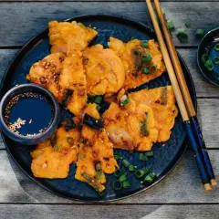 Knusprige Kimchi-Pfannkuchen mit Frühlingszwiebeln und Sesam, serviert mit Dip und Stäbchen.