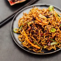 Ein Teller mit leckerem Chow Mein, garniert mit Frühlingszwiebeln und Karotten. Perfekt für ein schnelles, herzhaftes Essen.