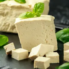 Frisch geschnittener Tofu, einige Würfel und ein ganzer Block, garniert mit Basilikum. Dieser ist tofu fermentiert und bereit für die Zubereitung.