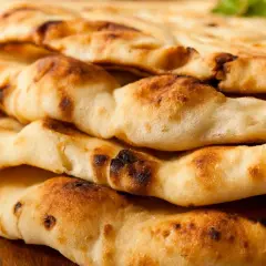 Gestapeltes, goldbraunes Naan-Brot mit leicht verbrannten Stellen. Dieses Fladenbrot ist ein Grundnahrungsmittel der indischen Küche.