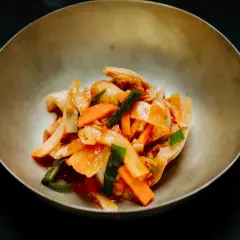 Kimchi mit Karotten und Frühlingszwiebeln, gewürzt mit Gochugaru, in einer Schale.