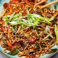 Chao mian Nudeln mit Gemüse, garniert mit Frühlingszwiebeln und Sesam.