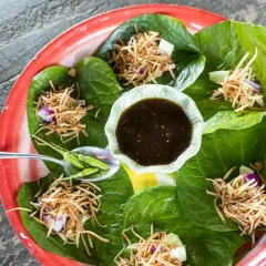 Miang Kham: grüne Blätter gefüllt mit knusprigen Nüssen, Zwiebeln und Limette, serviert mit Dip und Chilis.