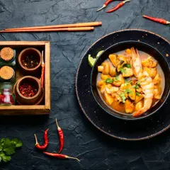Würziges Meeresfrüchte-Curry mit Garnelen und Muscheln, daneben Gewürze. Was ist Fischsauce? Sie verleiht diesem Gericht Tiefe.