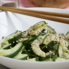 Frischer, knackiger koreanischer Gurkensalat mit Sesam bestreut, bereit zum Genießen mit Stäbchen.
