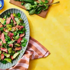 Würzig-frischer Rindfleischsalat Thai mit zarten Rindfleischstreifen, Gurken, Tomaten und Kräutern, garniert mit Limettenspalten.