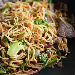 Leckere asiatische Nudeln kochen mit Rindfleisch, Brokkoli, Karotten und Paprika in einem Wok.