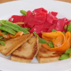 Bunte Reisnudeln kochen mit gebratenem Tofu, Karotten und Zuckerschoten. Ein farbenfrohes Gericht, das Lust auf mehr macht.