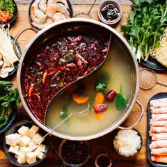 Eine köstliche asiatische Suppe mit zwei Brühen, Fleischscheiben, Garnelen, Pilzen, Gemüse, Tofu und Nudeln.