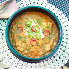 Herzhafte Doenjang Suppe mit Enoki-Pilzen und scharfen Chilischeiben, serviert in einer traditionellen Schüssel.