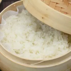 Frisch gedämpfter Klebreis kochen in einem Bambuskorb. Perfekt für asiatische Gerichte.
