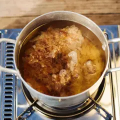 Ein Topf mit kochendem Wasser, in dem sich Flocken von Dashi no moto befinden, die ihren Umami-Geschmack freisetzen.