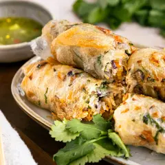 Knusprige Frühlingsrollen mit Reisnudeln und Gemüse, serviert mit Dip. Ein leckerer Snack, der niemanden ran lässt.