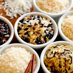 Verschiedene Reissorten in Schalen: schwarzer Reis, Basmati und eine Mischung. Ist Reis gesund? Ja, diese Vielfalt zeigt, wie gesund Reis sein kann.