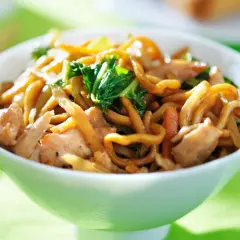 Eine Schüssel mit dampfenden Lo Mein Nudeln, Hühnchen und Gemüse, bereit zum Genießen.