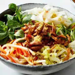 Herzhafte Reisnudel bowl mit zartem Fleisch, knackigem Gemüse und frischer Minze.
