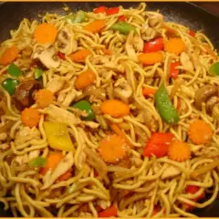 Ein Teller mit leckeren Mi Nudeln, garniert mit Hühnchen, Karotten, Pilzen und Paprika.