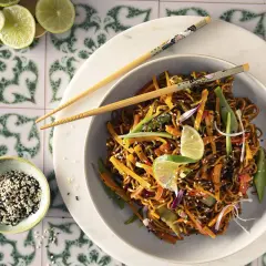 Asia Nudel mit Gemüse und Sesam, garniert mit Limettenspalten. Ein Gericht, das Fernweh weckt.