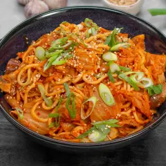 Eine Schüssel mit würzigem Kimchi Ramen, garniert mit Frühlingszwiebeln und Sesam.