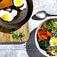 Ein köstliches Bibimbap-Rezept: Bunte Schüssel mit Reis, Gemüse, Rindfleisch, Pilzen und Spiegelei, garniert mit schwarzen Sesamkörnern.