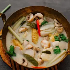Eine Schüssel mit cremigem Tom Kha mit Pilzen, Zitronengras und Chili. Die Tom Kha Sauce duftet aromatisch.