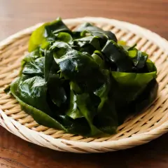 Ein Haufen glänzender, dunkelgrüner Seetang liegt auf einem geflochtenen Korbe. Dieser seetang gesund ist eine köstliche und nahrhafte Ergänzung für jede Mahlzeit.