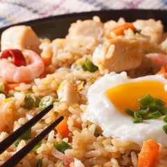 Nasi Goreng mit Garnelen, Hühnchen und einem Spiegelei, garniert mit Frühlingszwiebeln. Ein köstliches Gericht!