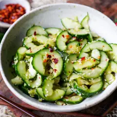 Frischer, asiatischer Gurkensalat in Spiralen, garniert mit Sesam und Chili-Flocken. Ein leichter Genuss.