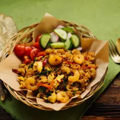 Ein authentisches nasi goreng rezept original mit Garnelen, Ei und frischem Gemüse. Serviert im Korbe, mit Gurken und Tomaten.