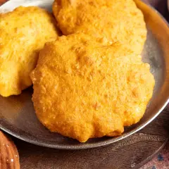 Drei goldbraune, fluffige Bhatura Brote liegen auf einem Teller. Sie sind frisch frittiert und duften herrlich.