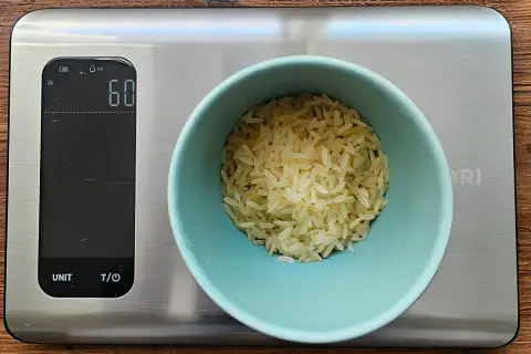 Eine Waage zeigt 60g Reis an. So behältst du die Reis Kalorien im Blick.