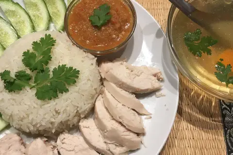 Khao man gai: Reis, Hähnchen, Gurkenscheiben, scharfe Sauce und eine klare Brühe mit Ei und Koriander.