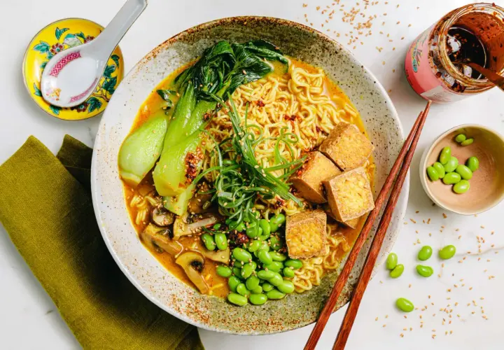 Schüssel mit Ramen-Nudeln, Bok Choy, Pilzen, Edamame und Tofuwürfeln. Die Vielfalt der **ramen toppings** macht dieses Gericht unwiderstehlich.
