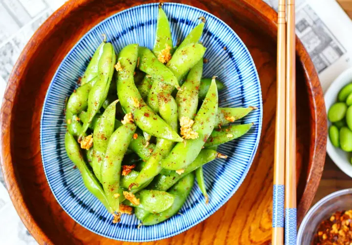 Schüssel mit gewürzten Edamame-Schoten, eine gesunde Quelle für Edamame Proteine, bereit zum Genuss mit Stäbchen.