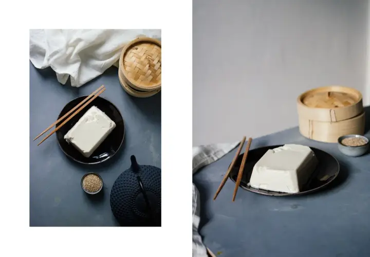 Ein Block Seidentofu auf einem Teller, daneben Stäbchen, eine Teekanne und Sesam. Was ist Seidentofu? Zart und cremig, ideal für asiatische Gerichte.