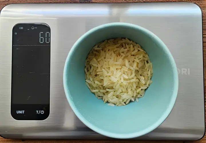 Eine Waage zeigt 60g Reis an. So behältst du die Reis Kalorien im Blick.