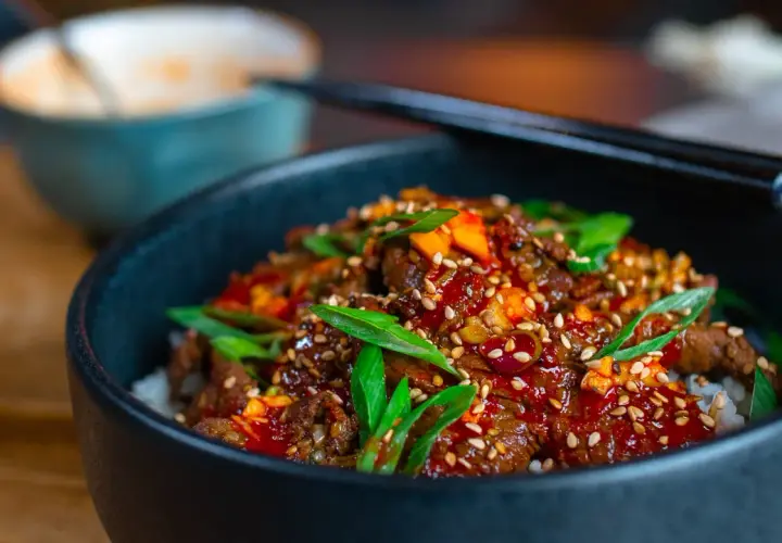 Schüssel mit Reis und würzigem Rindfleisch, garniert mit Frühlingszwiebeln und Sesam. Eine köstliche bulgogi sauce alternative.