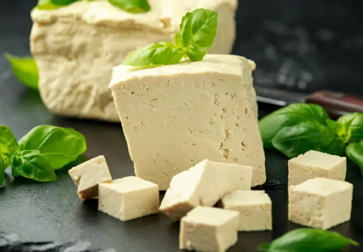 Frisch geschnittener Tofu, einige Würfel und ein ganzer Block, garniert mit Basilikum. Dieser ist tofu fermentiert und bereit für die Zubereitung.