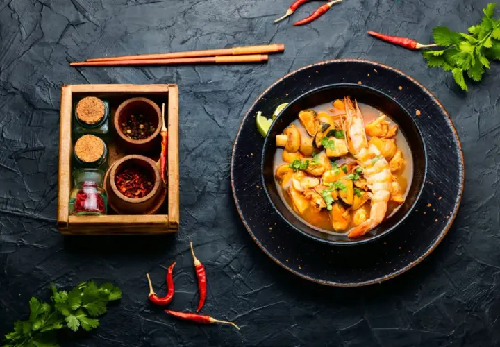 Würziges Meeresfrüchte-Curry mit Garnelen und Muscheln, daneben Gewürze. Was ist Fischsauce? Sie verleiht diesem Gericht Tiefe.