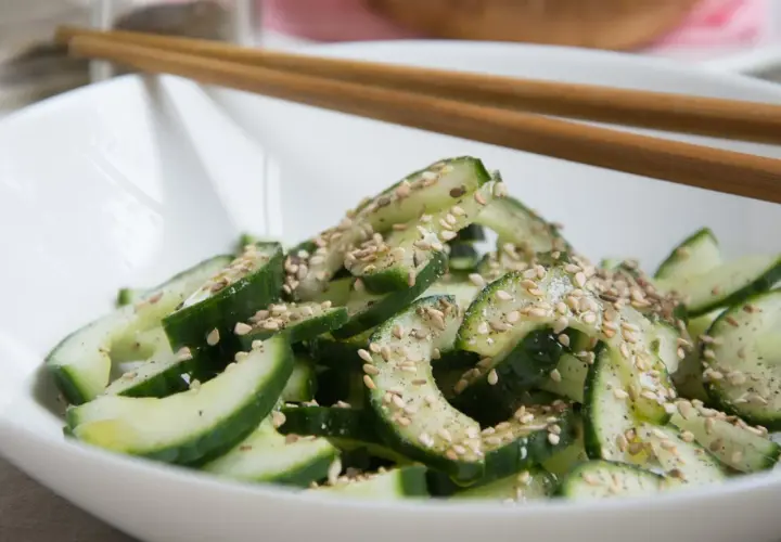 Frischer, knackiger koreanischer Gurkensalat mit Sesam bestreut, bereit zum Genießen mit Stäbchen.