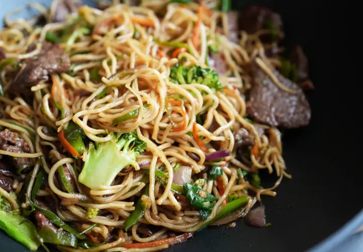 Leckere asiatische Nudeln kochen mit Rindfleisch, Brokkoli, Karotten und Paprika in einem Wok.
