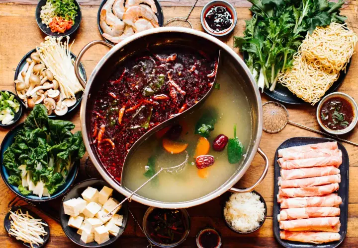 Eine köstliche asiatische Suppe mit zwei Brühen, Fleischscheiben, Garnelen, Pilzen, Gemüse, Tofu und Nudeln.