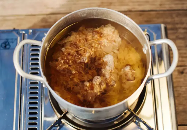 Ein Topf mit kochendem Wasser, in dem sich Flocken von Dashi no moto befinden, die ihren Umami-Geschmack freisetzen.
