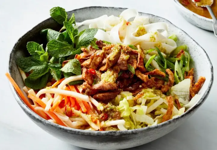 Herzhafte Reisnudel bowl mit zartem Fleisch, knackigem Gemüse und frischer Minze.