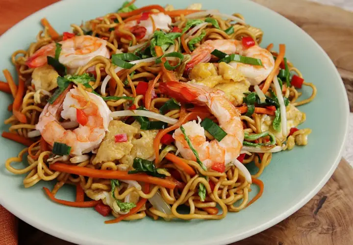 Mi Quang: Nudeln mit Garnelen, Karotten, Ei und Frühlingszwiebeln auf einem Teller.